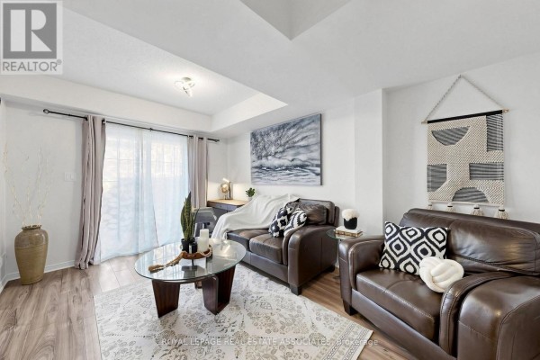Living room with brown leather sofas, a glass coffee table, and large sliding glass doors. - 22 Benjamin Way, Whitby