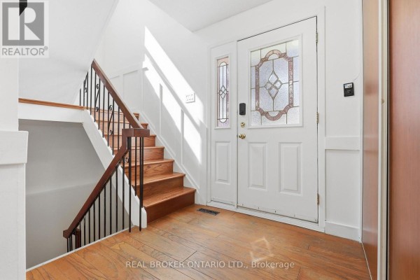 Interior entryway with a white door, stained glass sidelight, wood floors, and a staircase. - 22 Bent Oak Circle, Mississauga