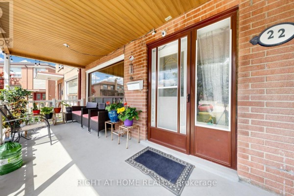 Close-up of the covered front porch with seating, plants, and double glass doors. - 22 Brigham Court, Toronto