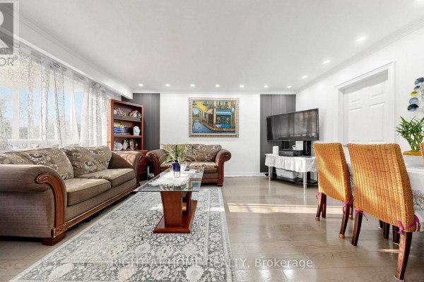 Living and dining area with hardwood floors, sofas, dining table, and television. - 22 Brigham Court, Toronto