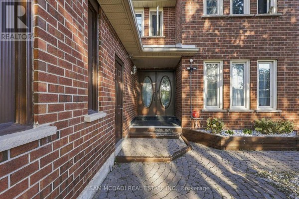 Close-up view of the double front doors with glass panels, surrounded by red brick exterior. - 22 Butlers Court, Brampton