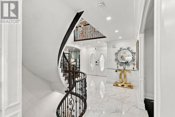 Foyer showcasing a curved staircase with black wrought iron railings, leading to the upper level. - 22 Butlers Court, Brampton