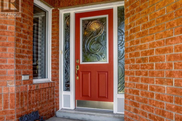 Close-up of a red front door with decorative glass panels, surrounded by brickwork. - 22 Canyon Hill Avenue, Richmond Hill