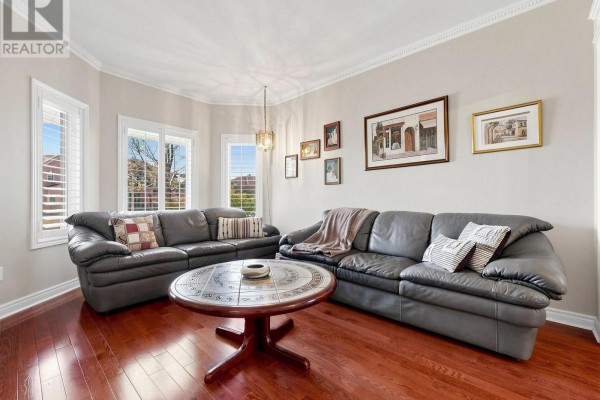 Living room with dark leather sofas, a round coffee table, and hardwood floors. - 22 Canyon Hill Avenue, Richmond Hill