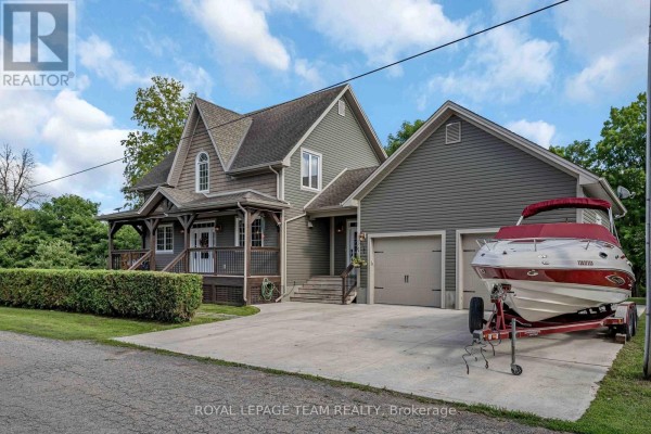 Close-up front view of a house with a covered porch and attached two-car garage, featuring a boat on a trailer. - 22 Centre Street, North Grenville