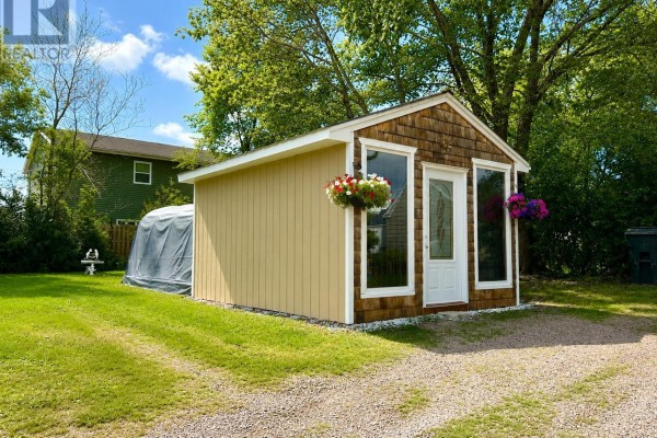 Exterior of a small yellow shed with a shingled roof and large windows. - 22 Chamberlain Street, Amherst