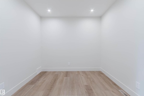 Empty room with white walls, recessed lighting, and light wood plank flooring. - 22 Clichy Cl, St  Albert