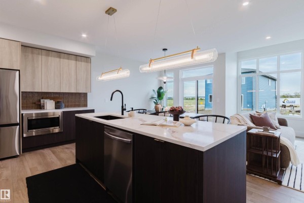 Open concept kitchen and living area with large windows overlooking a backyard and neighborhood construction. - 22 Clichy Cl, St  Albert