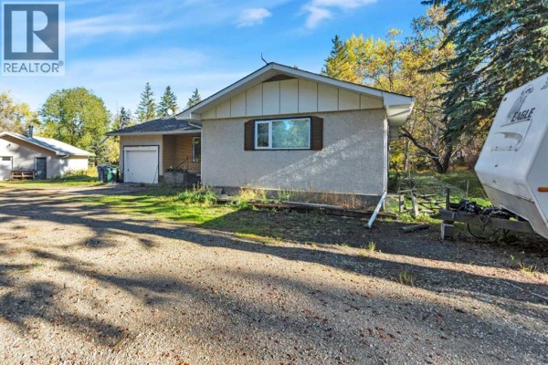 Exterior of a house with a garage, showing a side window and gravel driveway. - 22 College Park Close, Red Deer