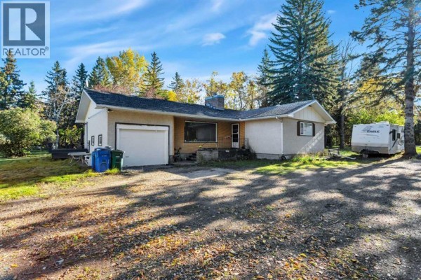Front view of a house with a garage, RV parking, and mature trees surrounding the property. - 22 College Park Close, Red Deer