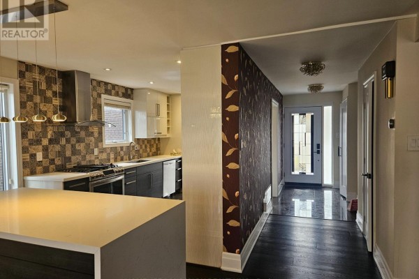 Modern kitchen with stainless steel appliances and dark wood floors. - 22 Coreydale Court, Toronto