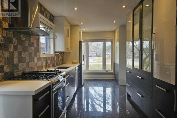 View of the kitchen from the island, showing a gas stove and window. - 22 Coreydale Court, Toronto