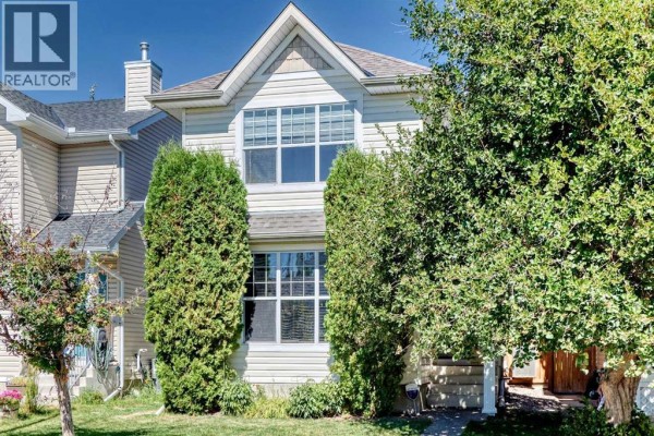 Front entrance of a house with a covered porch, walkway, and green lawn. - 22 Cramond Crescent Se, Calgary
