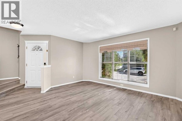 Living room featuring a gas fireplace with a white mantel and grey tile surround. - 22 Cramond Crescent Se, Calgary