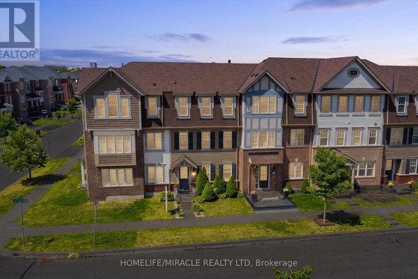 Front view of multi-story brick and vinyl townhouses with illuminated windows. - 22 Crossbill Road, Brampton