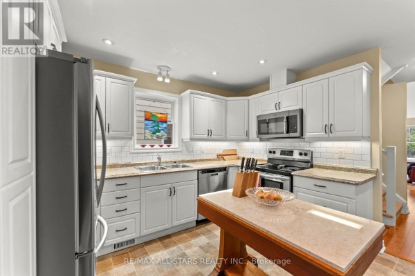 Front exterior of townhouses with double garage doors and manicured lawns. - 22 Deane Street, Kawartha Lakes