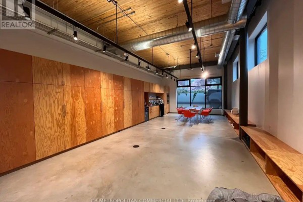 Another view of the open-concept office showing extensive wood cabinetry and furniture. - 22 Geary Avenue, Toronto