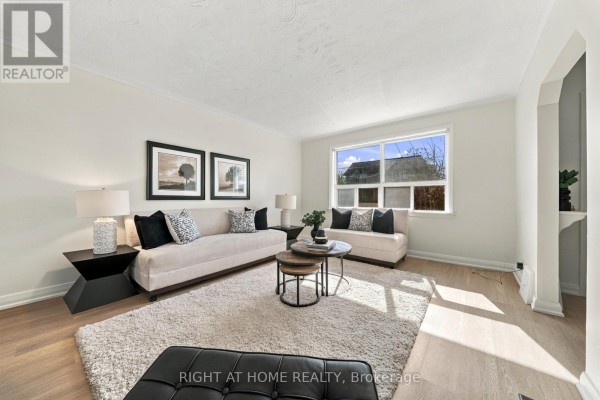 Living room with large window, sofas, coffee table, and light wood floors. - 22 Katherine Road, Toronto