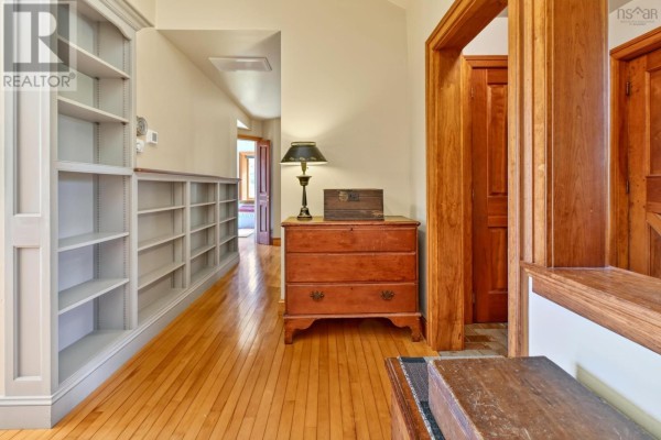 Dining area with wood table, chairs, built-in shelving, and large windows overlooking trees. - 22 Macken Road, Antigonish Landing