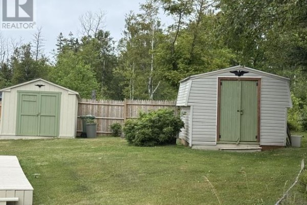 Two outdoor storage sheds with green doors and trim, separated by a wooden fence. - 22 Parkview Lane, Stanhope