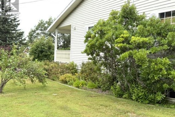 Landscaping with green bushes and trees in front of the bungalow's porch and siding. - 22 Parkview Lane, Stanhope