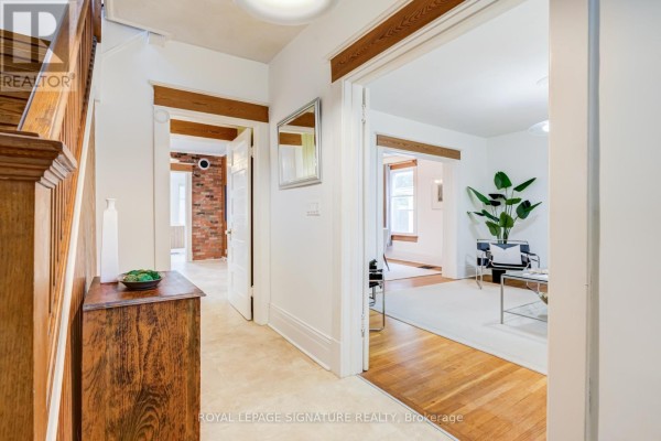 Interior hallway with wood accents, a wooden staircase, and doorways to other rooms. - 22 Peel Avenue, Brampton