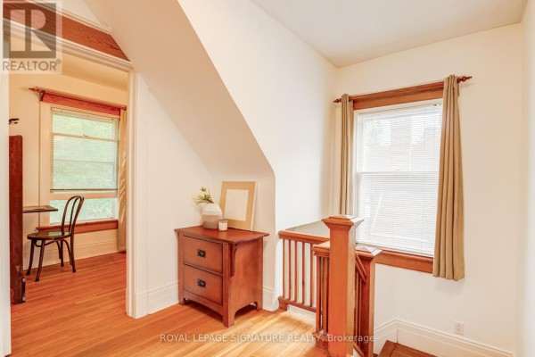 Wooden dresser, railing, desk, and chair in hallway - 22 Peel Avenue Brampton