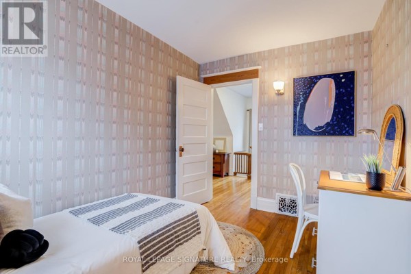 Bedroom with bed, desk, artwork, and patterned wallpaper - 22 Peel Avenue Brampton