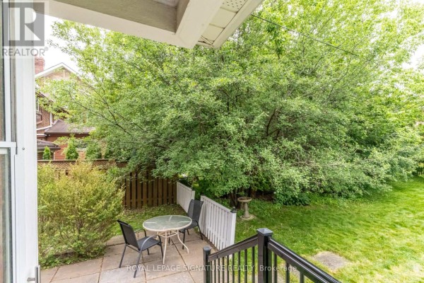 Patio with table and chairs overlooking green backyard - 22 Peel Avenue Brampton