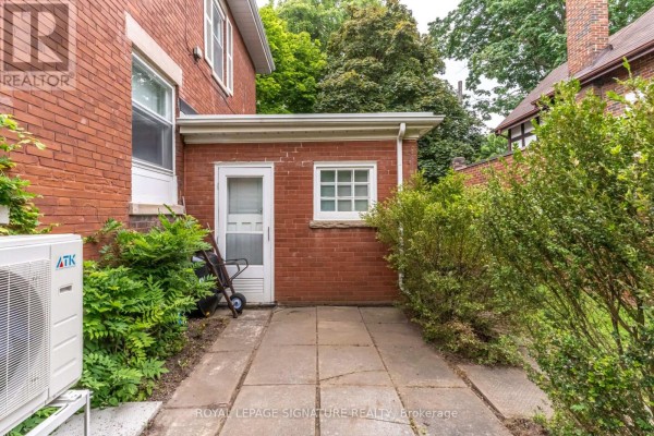 Brick exterior with paved patio, hedges, and AC unit - 22 Peel Avenue Brampton