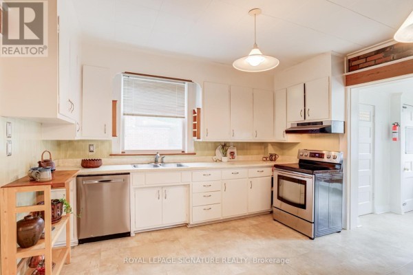 Kitchen with white cabinets, stainless steel appliances, and double sink - 22 Peel Avenue Brampton