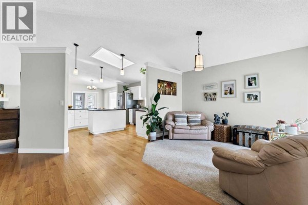 Open concept living room and kitchen with hardwood floors and white cabinets. - 22 Penland Way Ne, Medicine Hat