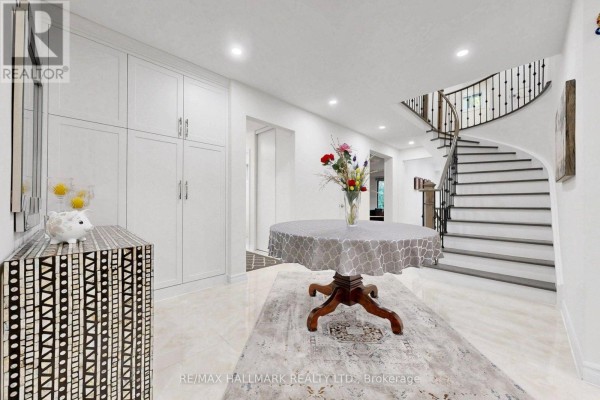 Spacious entryway with a round table, ornate rug, and a curved staircase. - 22 Pining Road, Markham