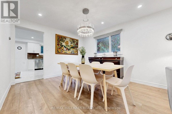 Dining room with a light wood table, six chairs, and a crystal chandelier. - 22 Pining Road, Markham