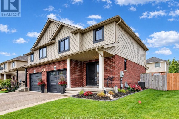 Side view of a townhouse with red brick and beige siding, showing a landscaped lawn. - 22 Poffenroth Path, Woolwich