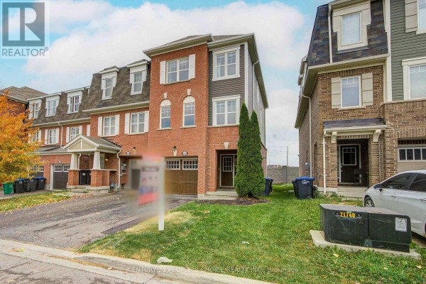 View of the townhouse exterior from the side showing the garage and lawn. - 22 Quillberry Close, Brampton