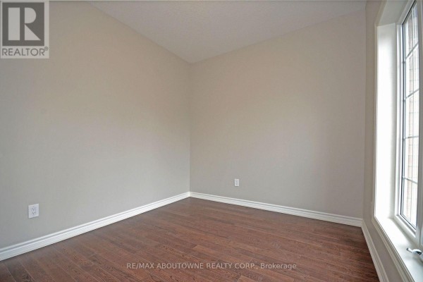 Empty room with beige walls, dark wood floors, and a large window on the right. - 22 Ryan Street, Centre Wellington
