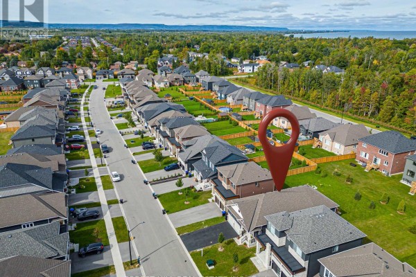 Aerial view of a suburban neighborhood with rows of houses and a distant treeline. - 22 Simona Avenue, Wasaga Beach