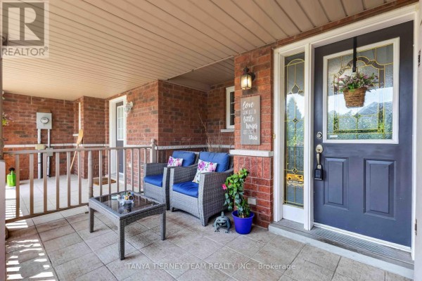Covered front porch of a townhouse with seating, brick exterior, and front door. - 22 Sinden Drive, Whitby