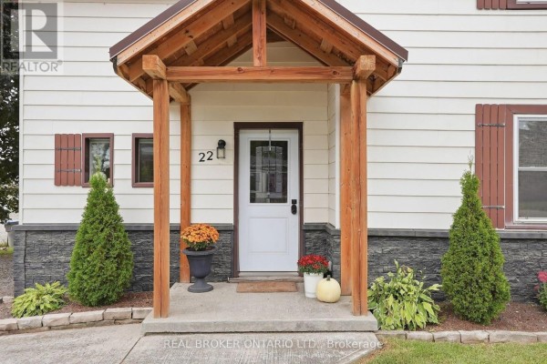 Close-up of the front entrance with a white door, wood-paneled porch roof, and decorative stone siding. - 22 Temperance Street, Perth East