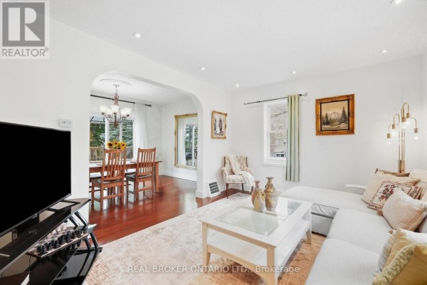 Living room with a white sectional sofa, coffee table, and arched entryway to a dining area. - 22 Temperance Street, Perth East