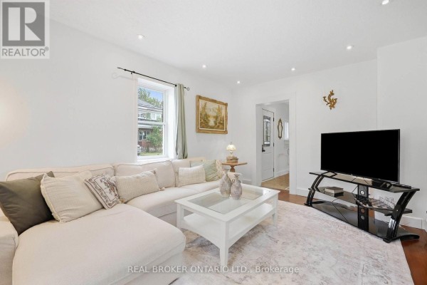 Living room featuring a sectional sofa, coffee table, and television, with a view into the entryway. - 22 Temperance Street, Perth East