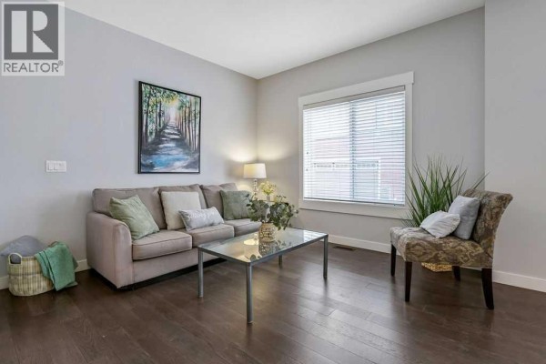 Living room featuring a grey sectional sofa, coffee table, television on a stand, and a window. - 22 West Coach Manor Sw, Calgary