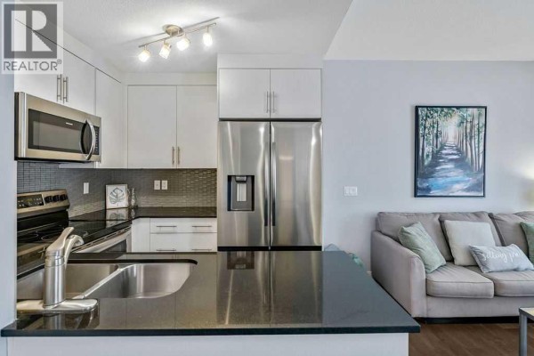 Kitchen with light grey cabinets, stainless steel appliances, and a dark granite countertop island. - 22 West Coach Manor Sw, Calgary