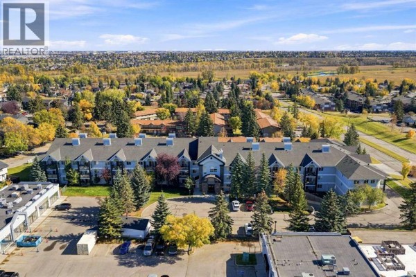 Aerial view of apartment building complex in a suburban setting with trees. - 220, 2022 Canyon Meadows Drive Se, Calgary