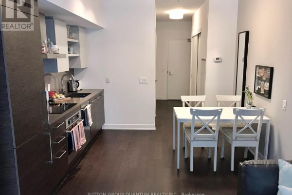 Kitchen with dark wood cabinets and stainless steel appliances, adjacent dining area. - 220 - 1030 King Street W, Toronto