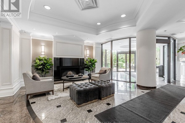 Apartment building lobby with marble floors, a fireplace, seating, and large windows. - 220 - 16 Dallimore Circle, Toronto