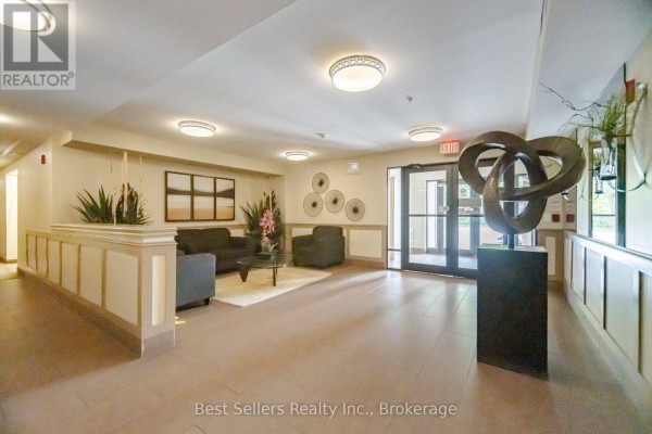 Apartment building lobby with seating area, elevators, artwork, and decorative plants. - 220 - 60 Mendelssohn Street, Toronto