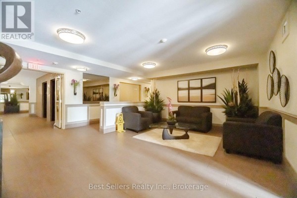 Lobby of the apartment building with seating, elevators, mirrors, and artwork. - 220 - 60 Mendelssohn Street, Toronto