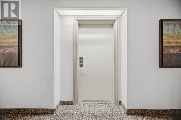 Close-up of an apartment door in a hallway with decorative artwork on the walls. - 220 - 60 Mendelssohn Street, Toronto